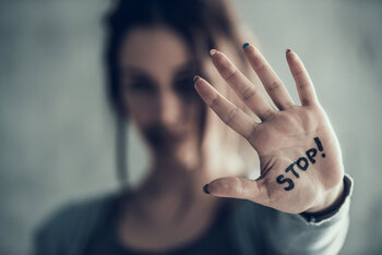 Eine junge Frau hält ihre Handfläche mit der Aufschift "Stop!" in die Kamera