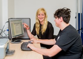 Zwei Jugendliche sitzen vor einem Computer.