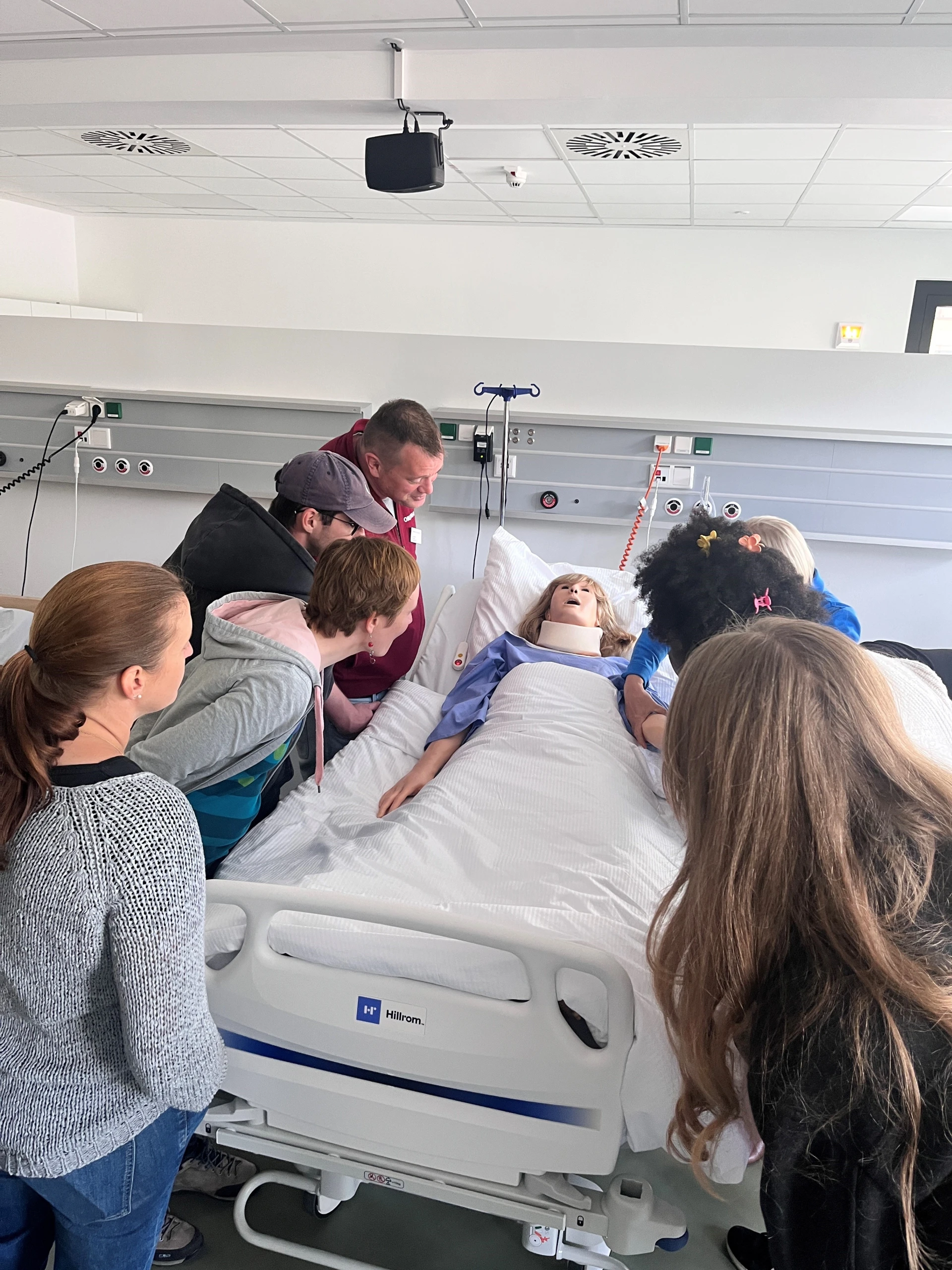 Pflegefachschüler:innen lernen an einer Pflegepuppe.