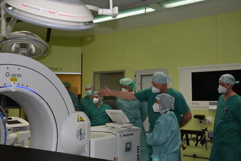 Chefarzt Dr. Dirk Schulze Bertelsbeck zeigt der Ministerin den O-Arm, ein Röntgengerät, das sich während der Operation um den Patienten schließt, dreidimensionale Röntgenbilder erzeugt, und so dem Operateur millimetergenaues Agieren im sensiblen Bereich der Wirbelsäule ermöglicht.
