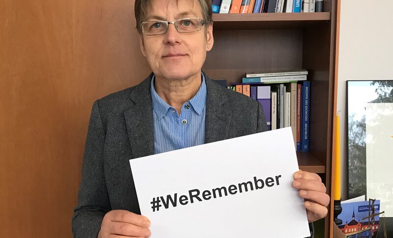 Barbara Eschen hält ein Bild mit #WeRemember hoch