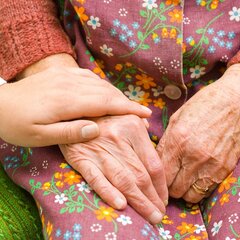 Eine Hand hält tröstend die Hände einer älteren Person 