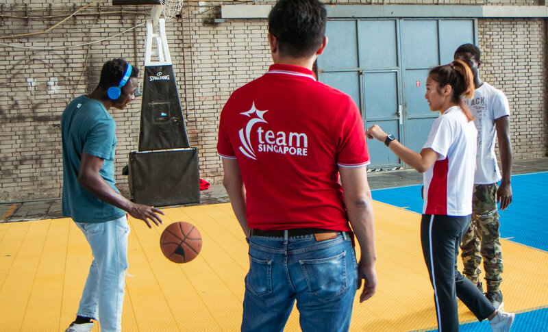 Vertreter der Singaporischen Delegation spielen Basketball mit jugendlichen Geflüchteten 